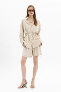 Sand beige linen belted shirt by MYT, long sleeve with a waist belt, styled with matching shorts for a casual look.